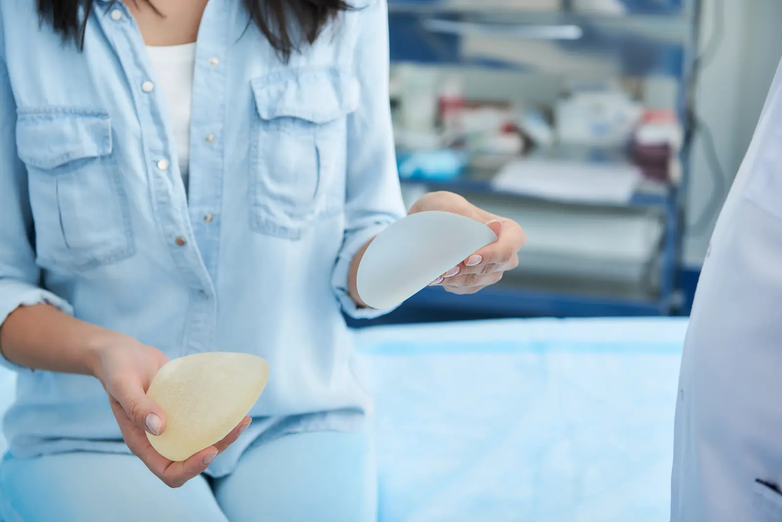 woman comparing breast implants consultation Woman holding breast implant options in consultation room.
